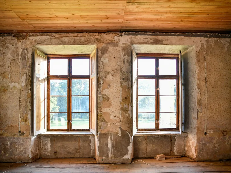 Period room stripped back for renovation, with two tall windows