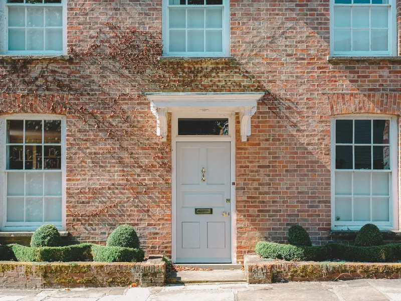 Red brick Georgian house with a pale front door and clipped hedges
